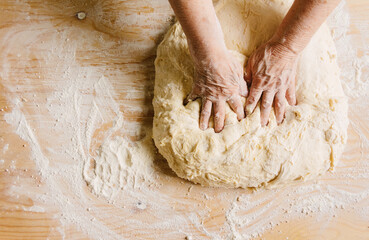 Cooking at home, old woman's hands kneading dough.
Empty copy space