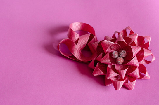 Decorative flower woven from a pink ribbon on a pink background.