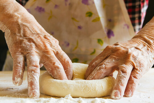 Cooking at home, old woman's hands kneading dough, getting the bread ready to be baked