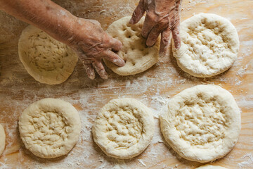 Cooking at home, old woman's hands getting the bread ready to be baked