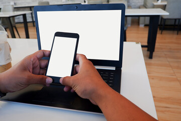 Cropped shot view of business man’s hands typing the labtop and holding smart phone with blank copy space screen for your information content or text message.