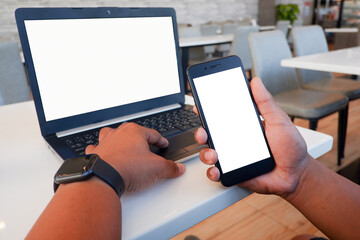 Cropped shot view of business man’s hands typing the labtop and holding smart phone with blank copy space screen for your information content or text message.