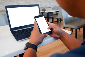 Cropped shot view of business man’s hands typing the labtop and holding smart phone with blank copy space screen for your information content or text message.