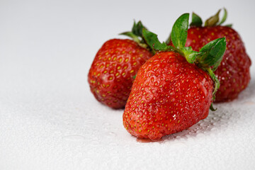 Fresh strawberries with soil particles on a white background.