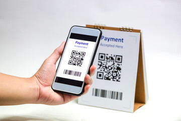 Hand holding smart phone to scan QR code payment on white background.