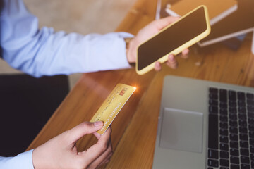 Online payment and shopping, Woman's hands holding credit card, smartphone eand using laptop computer for online shopping.