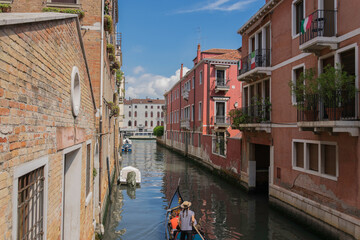 Small canal in Venice between old houses, with parked boats