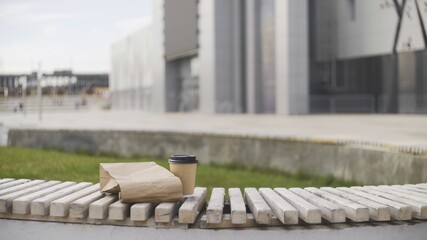 Obraz na płótnie Canvas Cup of coffee with paper bag on bench