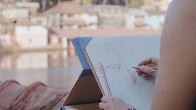 Faceless artist drawing landscape picture using pencils close up side view slow motion. Unrecognizable woman sitting outdoors with pencil paper canvas working alone macro detail. leisure time hobby