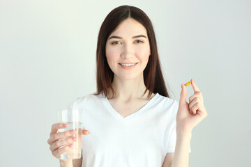 Young woman takes fish oil capsules at home
