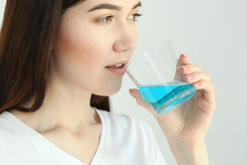 young girl uses mouthwash at home

