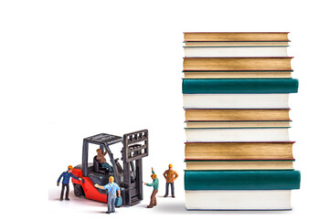 miniature worker driving forklift truck with stack vintage aged book isolated on white...