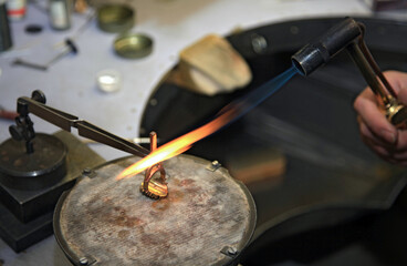 Hands of jeweler at work. Gas burner