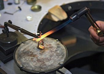 Hands of jeweler at work. Gas burner