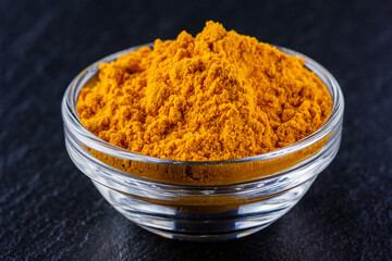 natural turmeric powder on a dark stone background