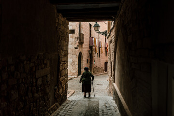 View of the medieval streets with and old woman walking, in Montblanc, Catalonia, Spain
