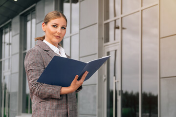 Stylish elegant woman of European appearance holds a folder with documents.
