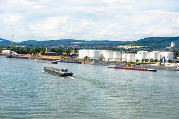 Fototapeta na wymiar A large tanker ship sailing in Germany on the Rhine river visible storage silos, fuel depot of petroleum and gasoline on the banks river, loading port, heavy sea traffic.