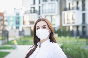 female doctor in protective mask stands outdoors