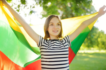 Cute young girl holding tricolor Lithuanian flag on Lithuanian Statehood Day.