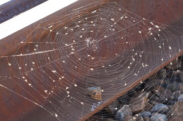 a large web hangs on rusty metal rails