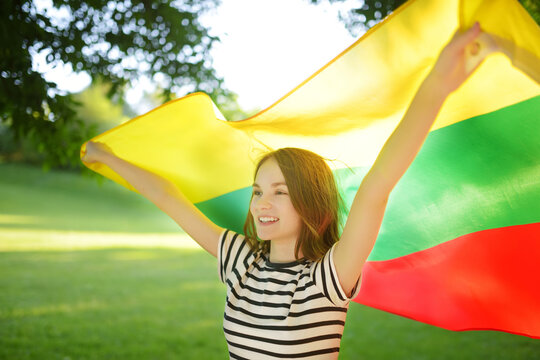 Cute young girl holding tricolor Lithuanian flag on Lithuanian Statehood Day.