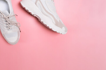 Modern stylish beige women's sneakers on pink background.