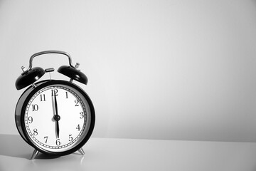 Wake up concept. Close up view of alarm-clock in morning bedroom environment. An image of a retro clock showing 06:00 am. 