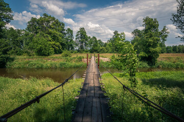 Fototapeta premium Wooden bridge over the Liwiec river at sunny day Korytnica, Masovia, Poland