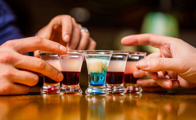 Friends drink shot or liqueur. Five glasses of alcohol.Tequila shots, vodka, whisky, rum. Cocktail at the nightclub. Group friends tequila shot glasses in bar. Male hands glasses of shot or liqueur