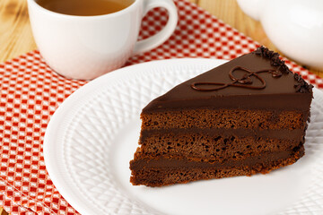 Piece of chocolate cake on white plate on table