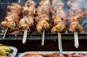 Grilling marinated shashlik on a grill. Shish kebab in the open air on the grill. Cooking meat on the street.
