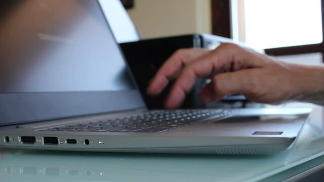 Hand Movement on the Keys of the Personal Computers, close-up to the side with the hand out of focus