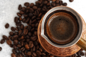Close up of copper coffee turk on light textured surface