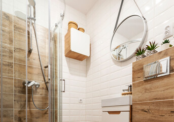 Interior of small white bathroom with wooden tiles , shower, round mirror, wash basin in design...