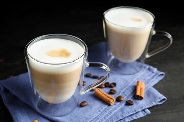 Delicious latte macchiato, cinnamon and coffee beans on grey table