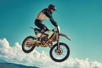 racer on mountain bike participates in motocross race, takes off and jumps on springboard, against...