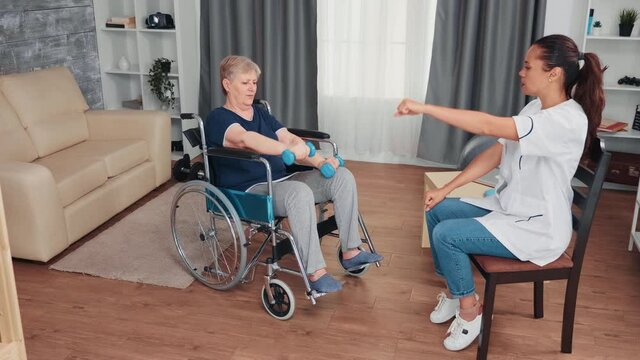 Invalid grandmother in wheelchair doing recovery therapy with doctor. Disabled handicapped old person recovering professional help nurse, nursing retirement home treatment and rehabilitation