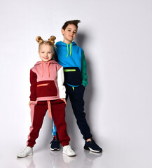 Kids, boy and girl, in colorful tracksuits, sneakers. They smiling, posing isolated on white studio...