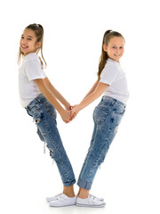 Two little girls hold hands, on a black background.