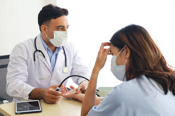 A woman or patient wear face mask and meet a doctor in hospital, headach or sick or coronar virus health checked and interview or blood pressure level screen check