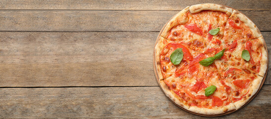 Top view of hot delicious pizza on wooden table, space for text. Banner design