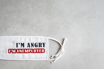 I'm angry. I’m unemployed. The inscription on a white medical mask on a light gray background. The concept of unemployment during coronavirus. Copy space for text