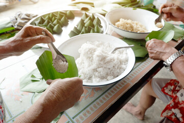 man and woman are confederate to Wrapped in local sweets with banana leaf   In occasion of Family Day and Songkran Festival of Thailand