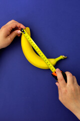 A measuring tape near a banana. The concept of penis enlargement, healthy eating, dieting and...