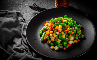 Mixed vegetables on a black plate on Dark grey black slate background