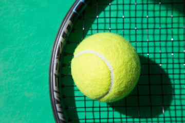 Close-up tennis ball on racket and green background. Concept in tennis.