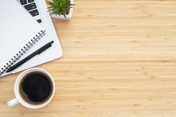 Modern wood office desk table with notepad, laptop computer and coffee cup with supplies. View from above with copy space. business workplace concept.