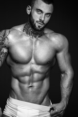 Sexy closeup portrait of handsome topless male model with beautiful eyes. Sexy man or muscular macho, bodybuilder, with muscle torso, body with six packs and abs poses on black background