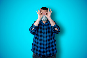 Emotional portrait of a bearded shocked man, amazed funny expression using mask isolated on blue background. Coronavirus concept